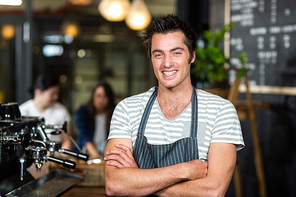 Smiling barista with arms crossed in a bar