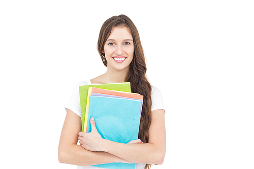 Portrait of smiling female college student holding books while standing on white background