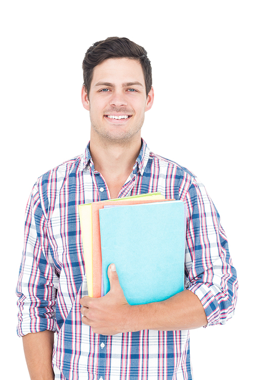 Portrait of smiling male college student holding books on white background