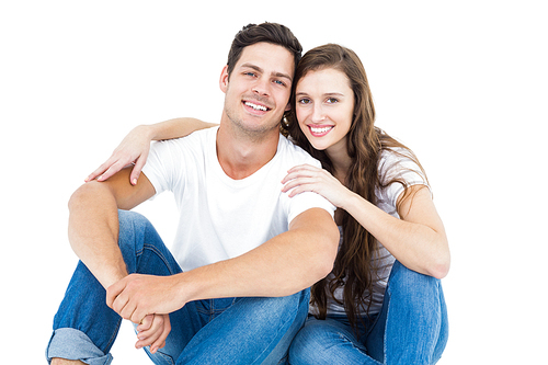 Young couple sitting on floor hugging on white background