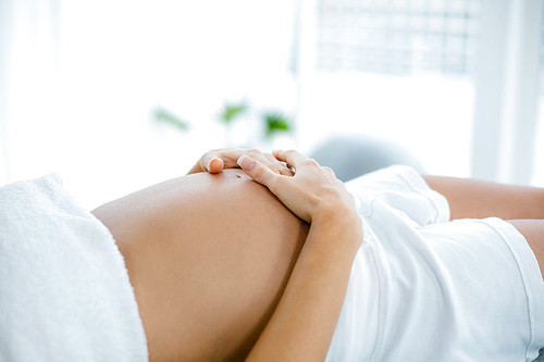 Pregnant woman relaxing on massage table at home