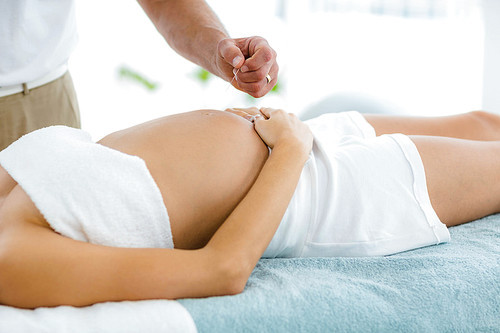 Pregnant woman receiving a spa treatment from masseur at home