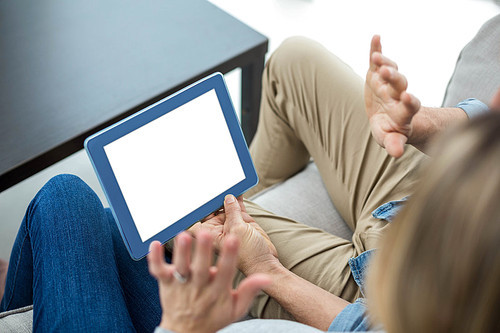 Couple sitting on sofa and using digital tablet