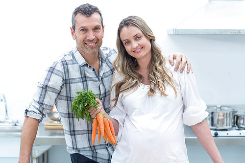Portrait of pregnant woman  while holding carrots