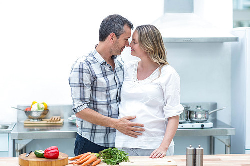 Man face to face with pregnant woman in their kitchen