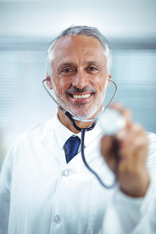 Happy doctor holding stethoscope in clinic