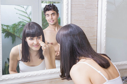 Woman looking in bathroom mirror and man looking at her