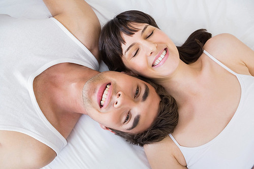 Happy couple lying on bed in bedroom