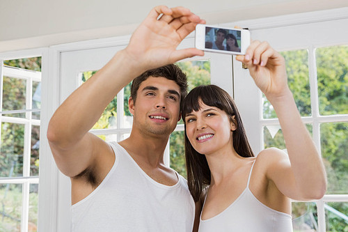 Young couple taking a selfie on mobile phone in living room