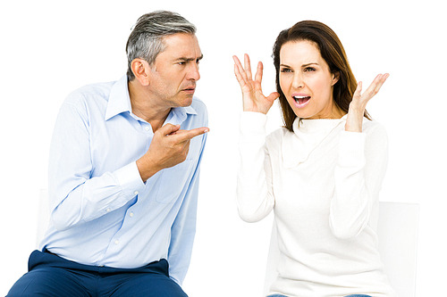 Couple arguing while sitting against white background