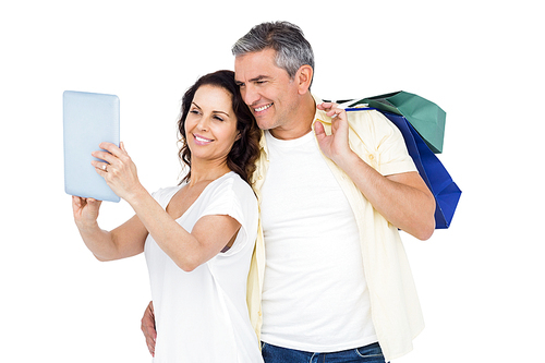 Couple with shopping bags looking at PC tablet against white background