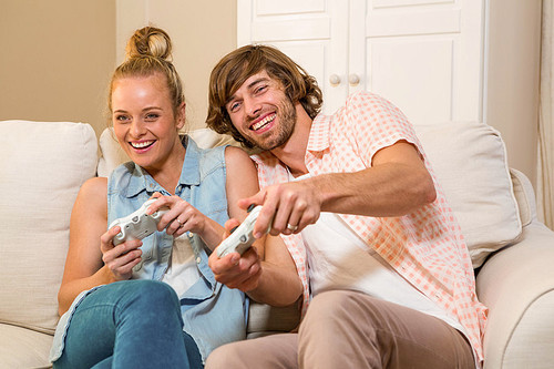 Cute couple playing video games sitting on the couch in the living room
