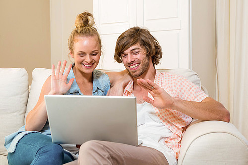 Cute couple using laptop sitting on the couch in the living room