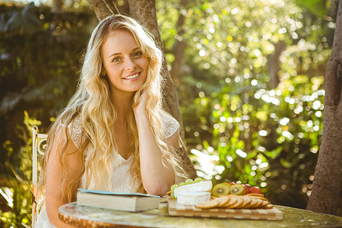 Beautiful blonde relaxing with a book and food in the garden
