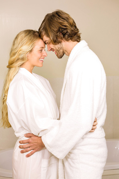 Cute couple embracing in bath robe in the bathroom at home