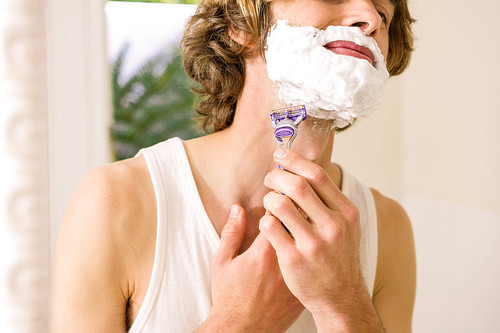 Handsome man shaving in the bathroom at home