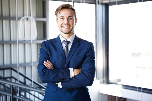 Portrait of businessman standing with arms crossed and smiling in office