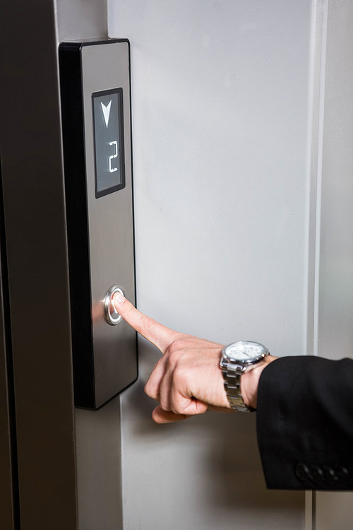 Businessman pressing elevator button in office