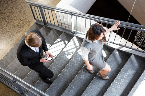 Businessman and businesswoman climbing staircase in office