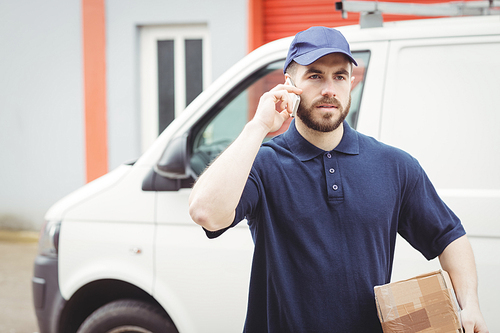 Delivery man making a phone call while holding a package