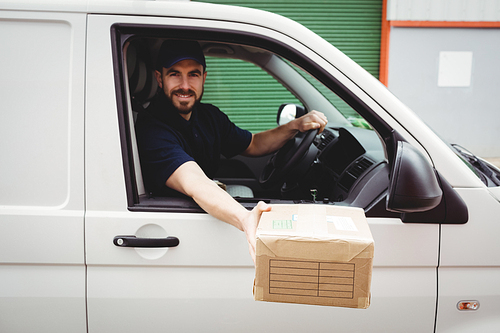 Delivery man sitting in his van while holding a package