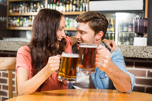 Couple toasting with beers at a bar