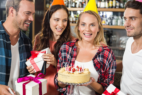 Woman  with cake in hands and friends around her