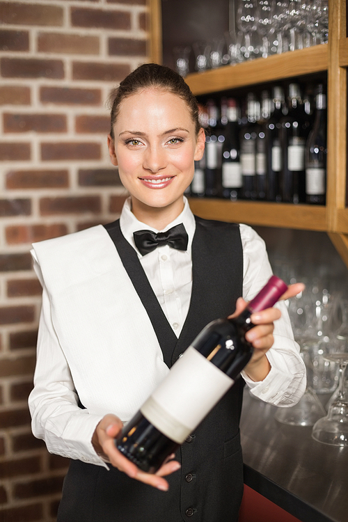 Beautiful barmaid holding a bottle of red wine