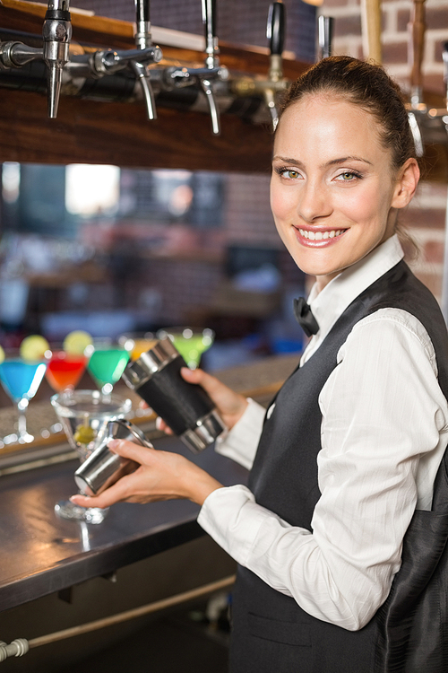 Beautiful barmaid pouring a cocktail in a bar