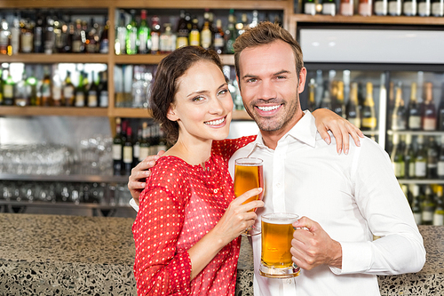 Smiling attractive couple holding beers while hugging