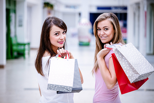 Portrait of two beautiful women holding shopping bags while shopping in mall