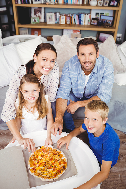 High angle portrait of family with pizza on table at home