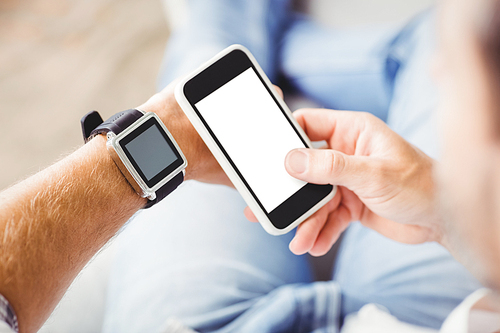 Man wearing smart watch and using smartphone at home