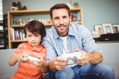 Smiling father and son playing video game at home