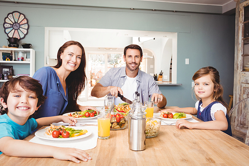 Portrait of happy family with food on dining table at home