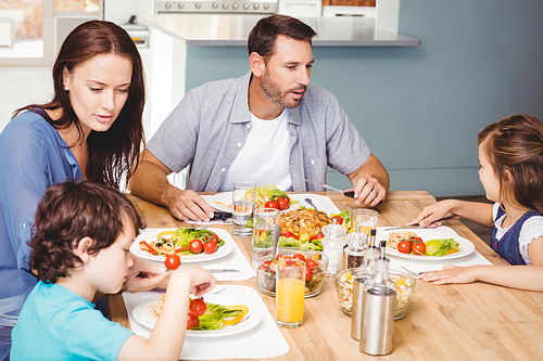 Family having lunch while sitting at dining table in home