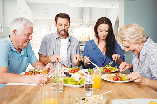 Family sitting at dining table with food in home