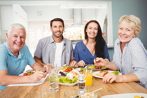 Portrait of family sitting at dining table with food in home