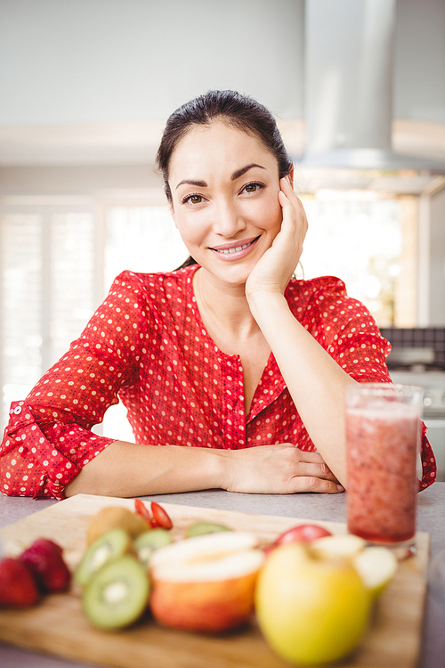 Portrait of happy woman with fruit juice on table at home