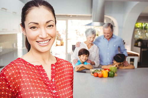 Portrait of happy woman with family preparing food in background