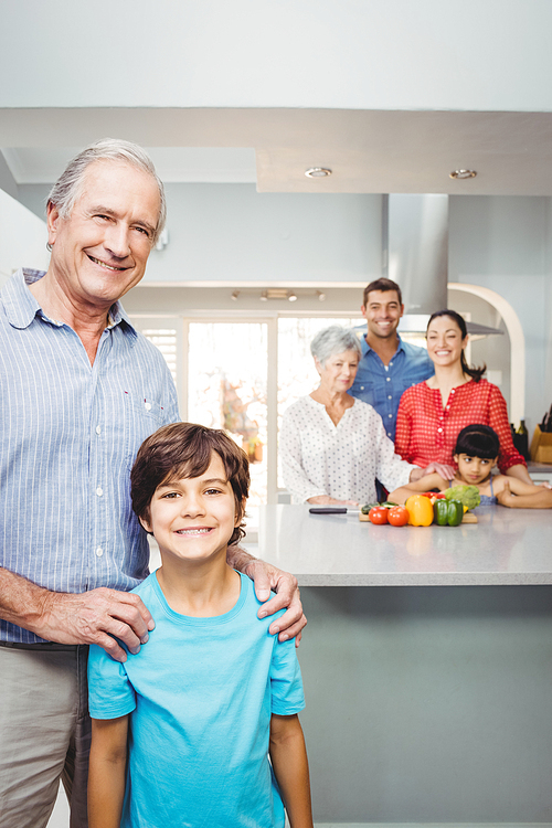 Portrait of happy boy with grandfather while family preparing food in background