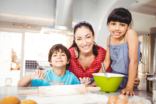 Portrait of happy woman with children preparing food at home