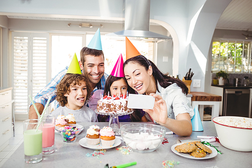 Family smiling while taking selfie during birthday celebration at home