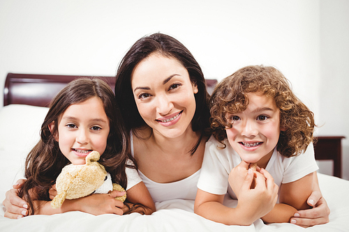Close-up of happy woman with children lying on bed at home