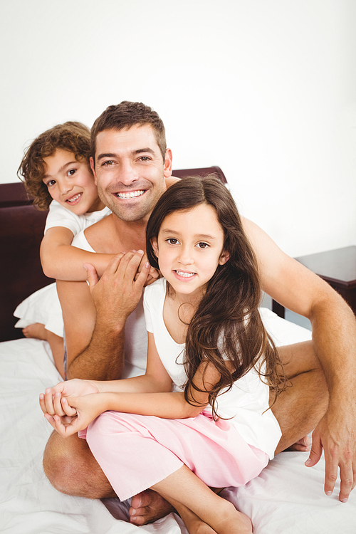 Close-up of happy father with daughter and son on bed at home