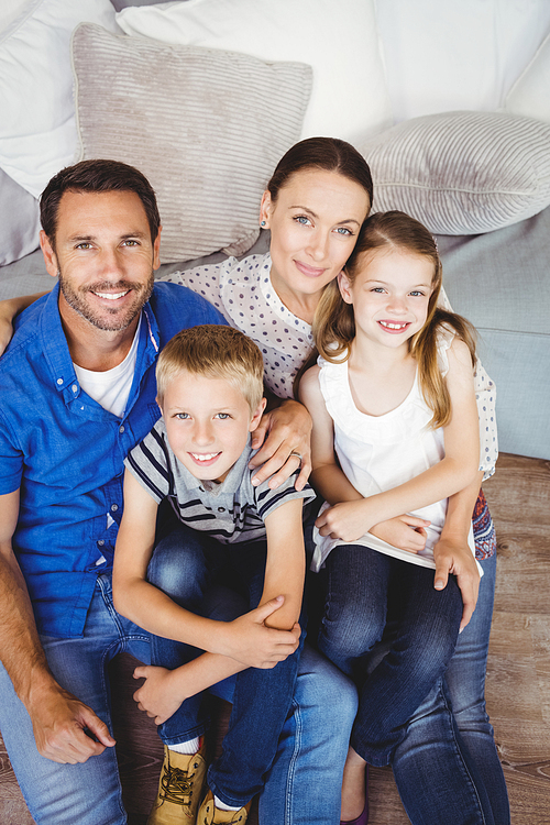 High angle portrait of happy family sitting by sofa in living room