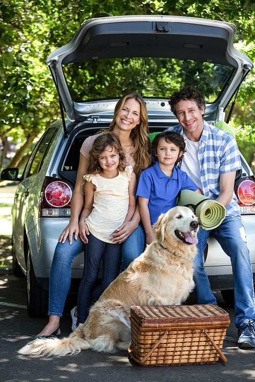 Smiling family sitting in the luggage space of a car