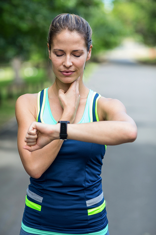 Sportswoman checking her heart rate watch in park