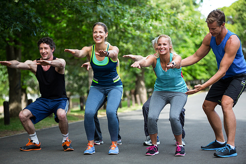 Fitness class doing squat sequence in the park