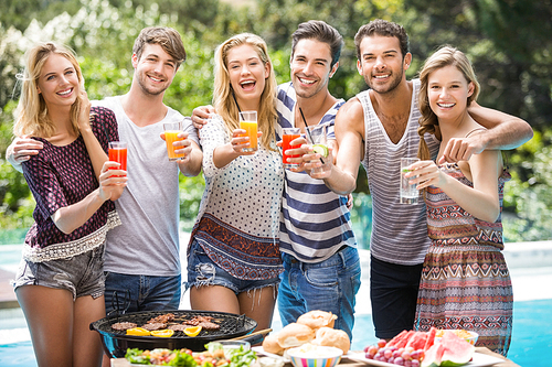 Portrait of friends having juice at outdoors barbecue party near pool